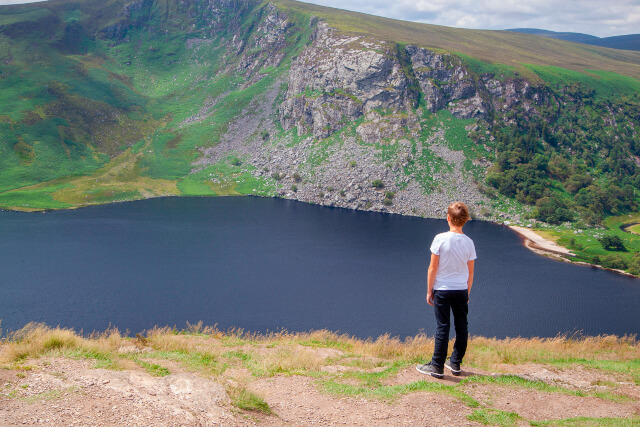 Boy stood looking down at lake on the Wicklow Mountains